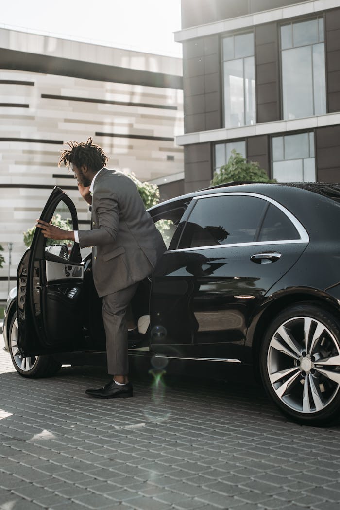The Art of Drawing Readers In: Your attractive post title goes here Stylish adult man in gray suit stepping out of a luxury black car in a modern city environment.